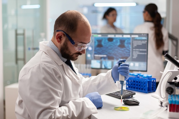 Scienziato biochimico sanitario che testa il campione di sangue utilizzando una micropipetta