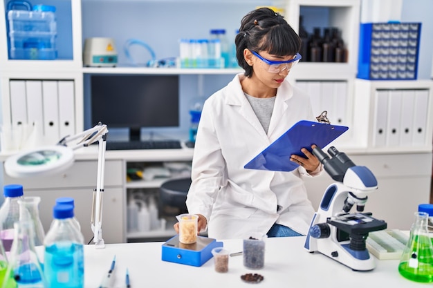 Scienziato della giovane donna che misura liquido al laboratorio