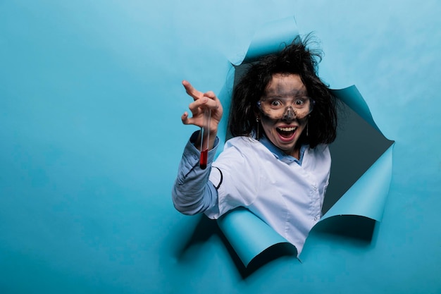 Scienziato lunatico con capelli disordinati e provetta di vetro sporca piena di campione di sostanza liquida. Chimico pazzo pazzo con espressione faccia buffa che tiene il pallone pieno di composti chimici.