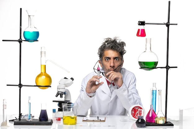 Scienziato maschio di vista frontale in vestito medico che tiene iniezione sul virus covid laboratorio di chimica scrivania bianca