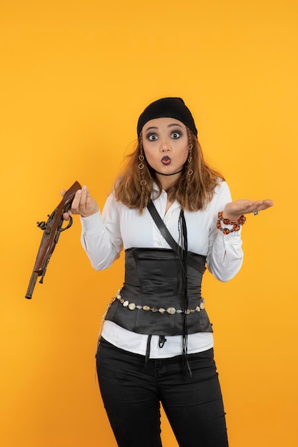 Scioccata giovane ragazza pirata in possesso di una pistola e guardando la telecamera. Foto di alta qualità