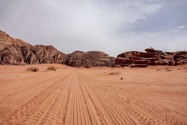 Scogliere e grotte in un deserto pieno di erba secca sotto un cielo nuvoloso durante il giorno