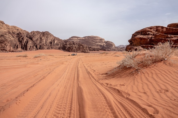 Scogliere e grotte in un deserto pieno di erba secca sotto un cielo nuvoloso durante il giorno