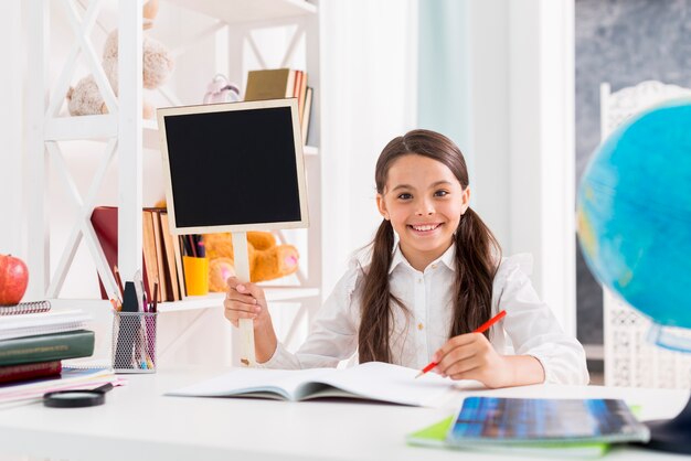 Scolara felice in uniforme che studia all&#39;aula