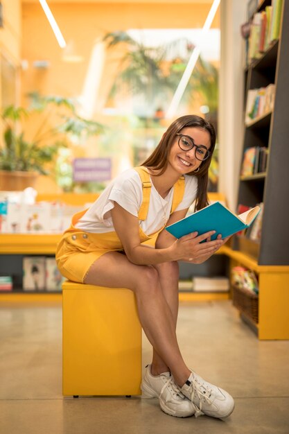 Scolara teenager che si siede con il libro sul banco