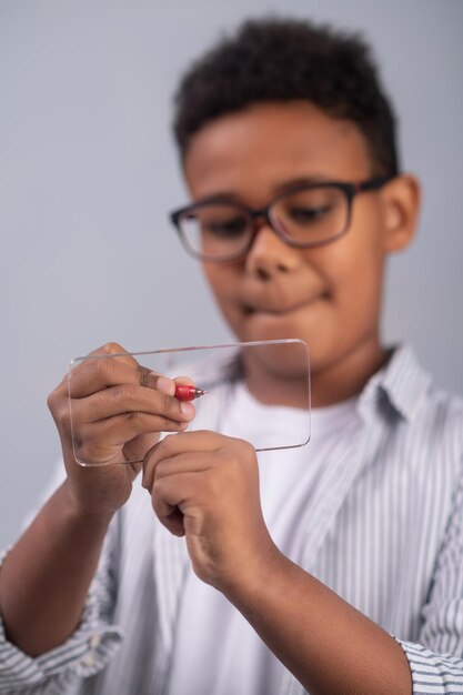 Scolaro occhialuto concentrato che disegna sulla diapositiva