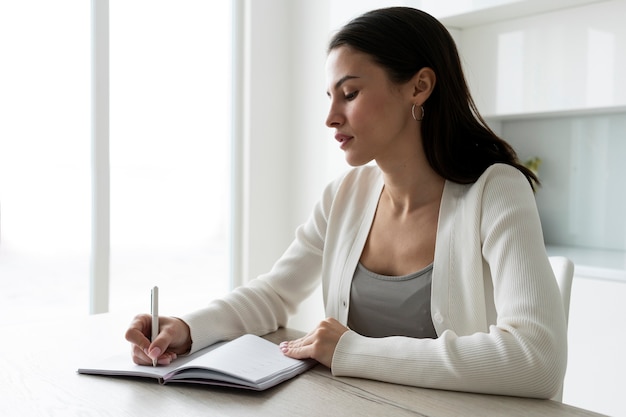 Scrittura della donna del colpo medio sul taccuino