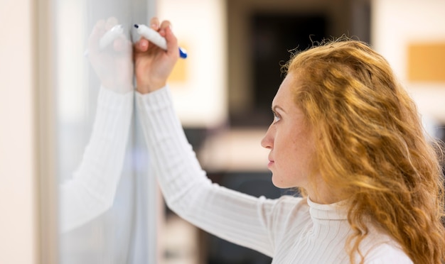 Scrittura focalizzata della donna di affari sulla lavagna