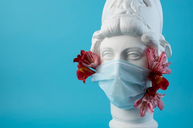 Scultura in marmo di figura storica con maschera medica e fiori