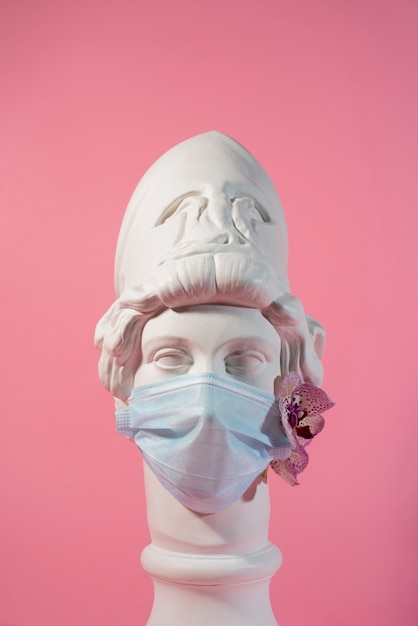 Scultura in marmo di figura storica con maschera medica e orchidea