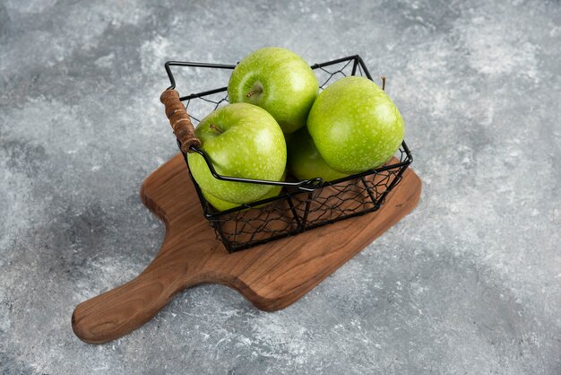 Secchio di metallo di mele verdi fresche su tavola di legno.