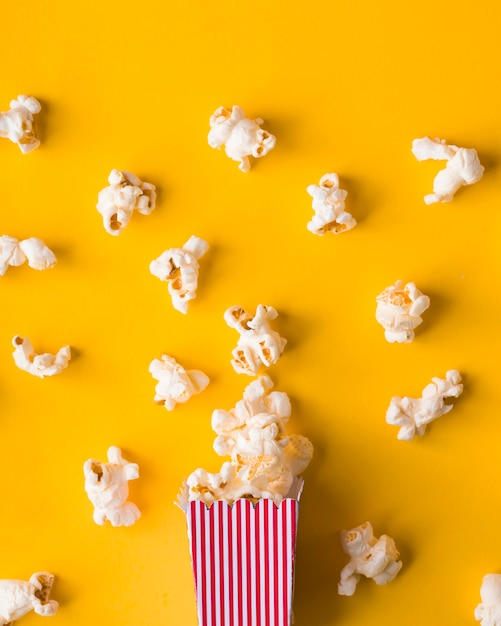 Secchio di popcorn piatto laici su sfondo giallo