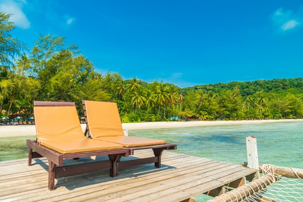 Sedia e letto sul molo di legno o ponte con spiaggia tropicale e mare nell&#39;isola paradiso