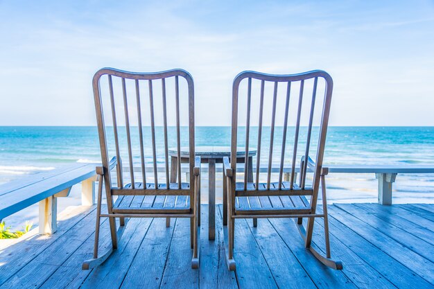 Sedia in legno vuota e tavolo al patio esterno con una bella spiaggia tropicale e mare