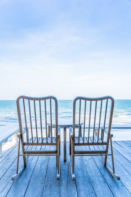 Sedia in legno vuota e tavolo al patio esterno con una bella spiaggia tropicale e mare