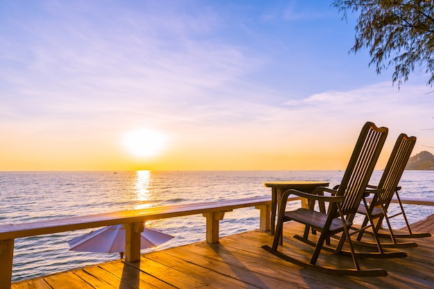 Sedia in legno vuota e tavolo al patio esterno con una bella spiaggia tropicale e mare