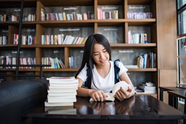 Seduta del libro di lettura della giovane donna dell&#39;interno in caffè urbano.