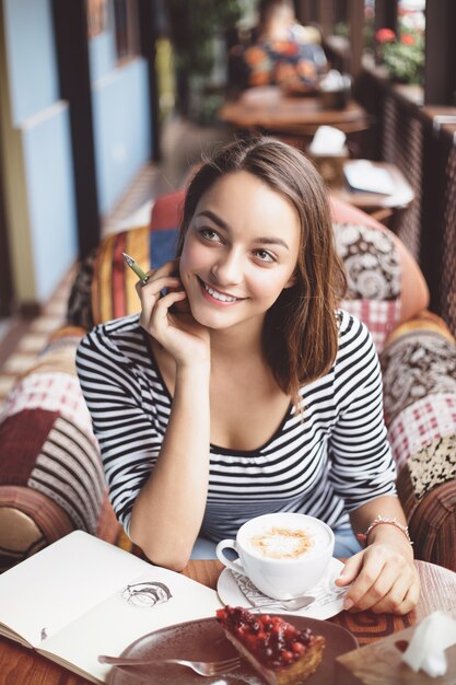 Seduta della giovane donna dell'interno in caffè urbano
