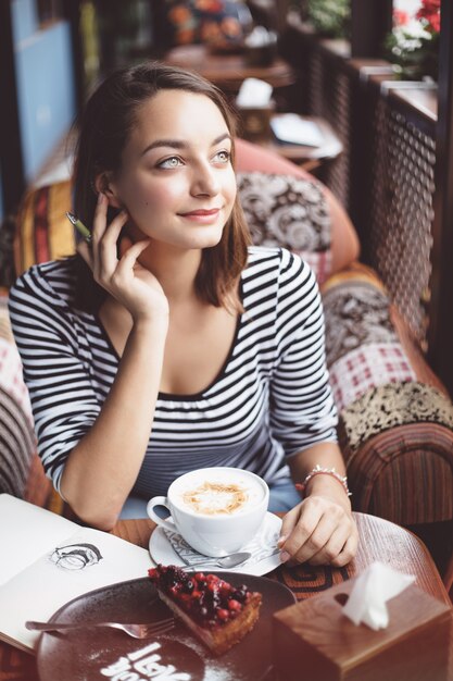 Seduta della giovane donna dell'interno in caffè urbano