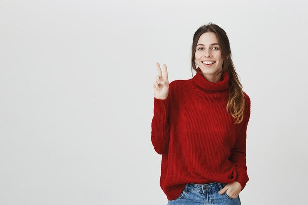 Segno di pace sorridente allegro di manifestazione della ragazza