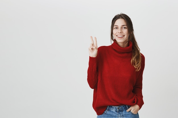 Segno di pace sorridente allegro di manifestazione della ragazza