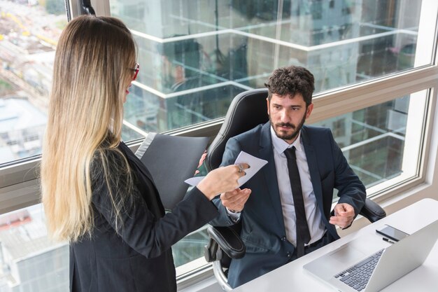 Segretaria femminile che dà documento al responsabile maschio sul posto di lavoro