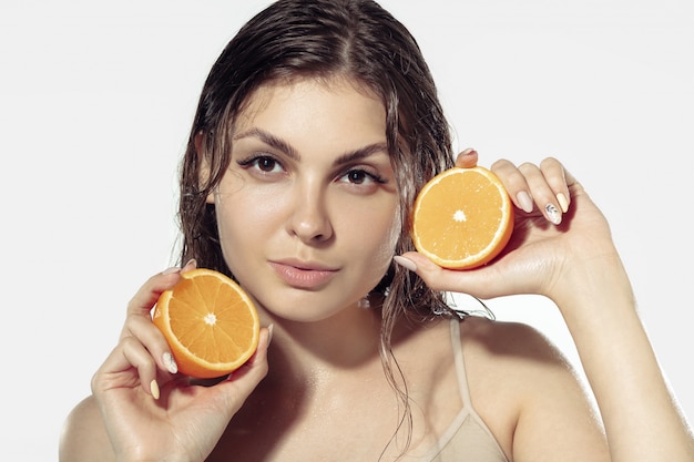 Segreti della gioventù. Bellissima giovane donna sul muro bianco. Cosmetici e trucco, trattamenti naturali ed ecologici, cura della pelle.