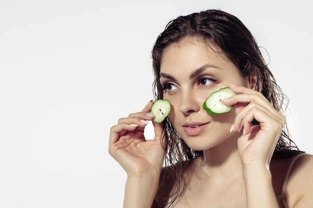 Segreti della gioventù. Bellissima giovane donna sul muro bianco. Cosmetici e trucco, trattamenti naturali ed ecologici, cura della pelle.