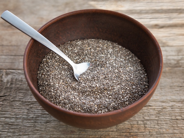 Semi nutrienti di chia in una ciotola su fondo di legno.