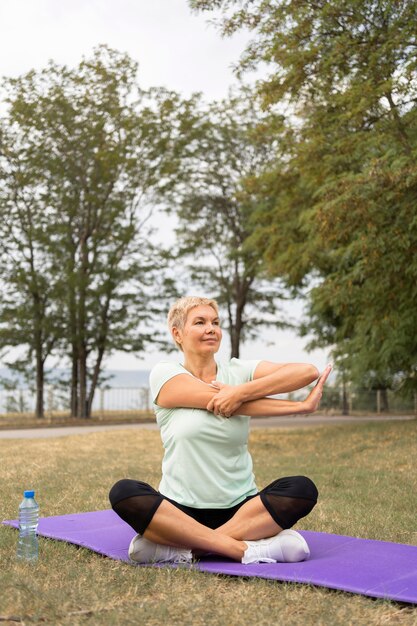 Senior donna a praticare yoga all'aperto nel parco