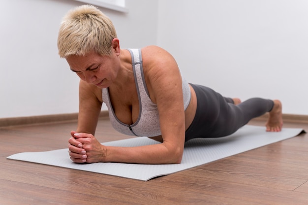 Senior donna al chiuso facendo esercizi di stretching