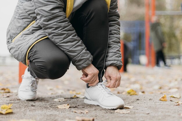 Senior donna che lega i lacci delle scarpe prima di lavorare all'aperto