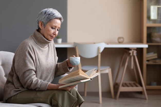 Senior donna che legge un libro a casa