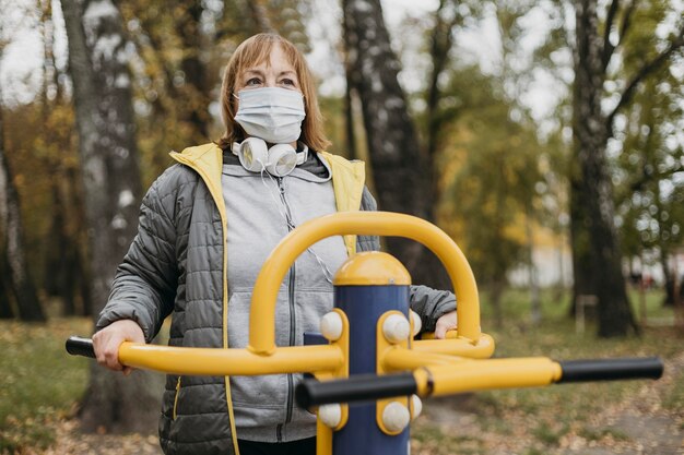 Senior donna con mascherina medica che lavora fuori all'aperto