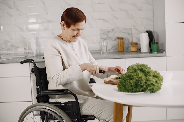 Senior donna in sedia a rotelle per la cottura in cucina. Persone disabili