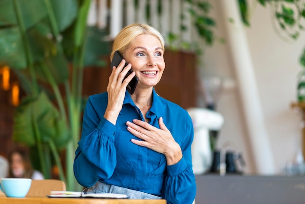 Senior donna parla al telefono mentre si lavora