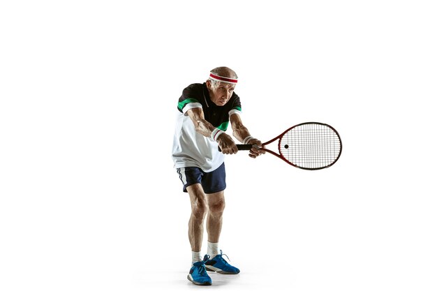 Senior uomo che indossa abbigliamento sportivo giocando a tennis isolato su sfondo bianco. Il modello maschile caucasico in ottima forma rimane attivo e sportivo. Concetto di sport, attività, movimento, benessere. Copyspace, annuncio.