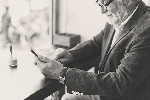 Senoir uomo caucasico utilizzando il telefono cellulare in cafe