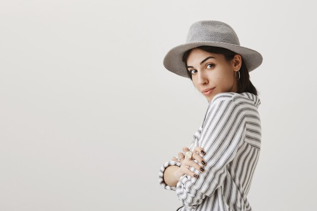 Sensuale donna alla moda in cappello grigio e camicetta guardando