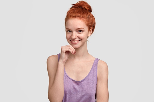 Sensuale femminile con capelli rossi, lentiggini, tiene la mano sotto il mento