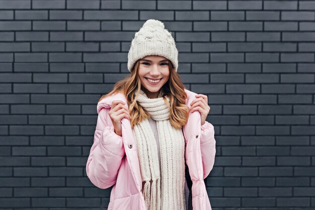 Sensuale giovane donna di buon umore in giro in una giornata fredda. Ritratto all'aperto di piacevole ragazza bionda in posa in cappello lavorato a maglia.