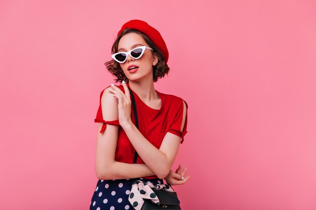 Sensuale signora bianca in cappello francese in posa. Foto dell'interno della ragazza riccia incredibile in berretto rosso che gode.