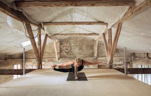 Senza peso. Una giovane donna atletica esercita lo yoga su un edificio abbandonato. Equilibrio della salute mentale e fisica. Concetto di stile di vita sano, sport, attività, perdita di peso, concentrazione.