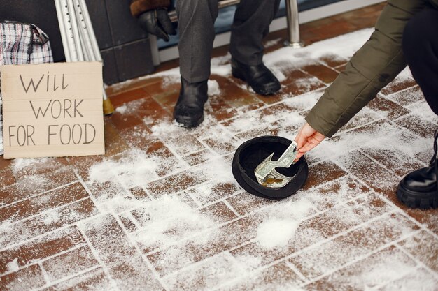 Senzatetto in una città invernale. Uomo che chiede cibo.