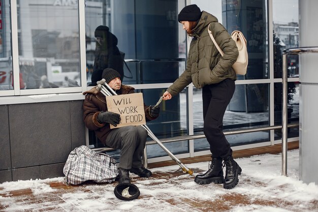 Senzatetto in una città invernale. Uomo che chiede cibo.