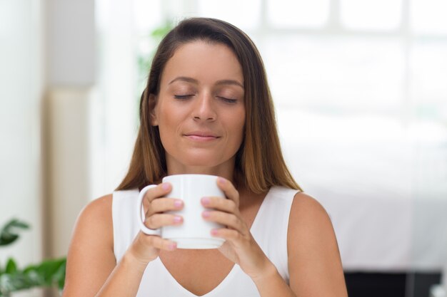 Serena giovane donna godendo il profumo di caffè