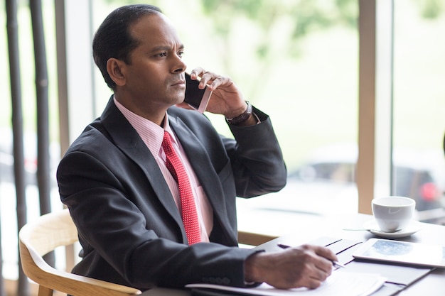 Serio business leader chiamata sul telefono nel caffè