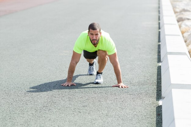 Serio forte uomo in posizione di partenza all&#39;aperto