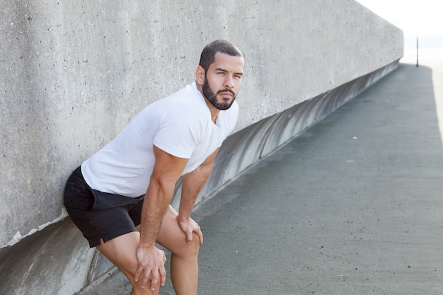 Serio muscolare sportivo uomo appoggiato al muro