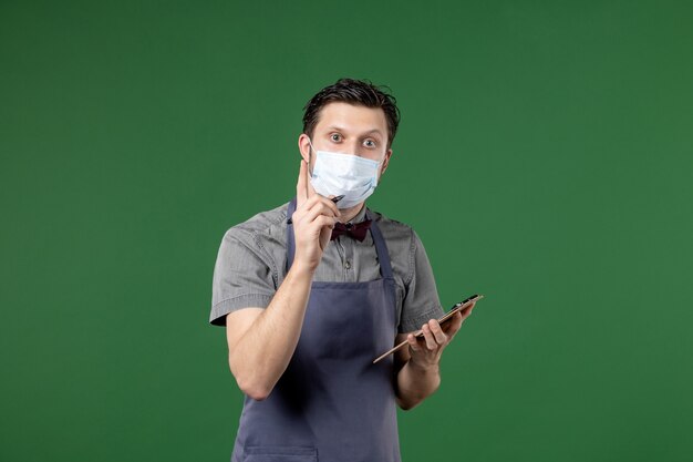 server per banchetti in uniforme con maschera medica e ordine su sfondo verde